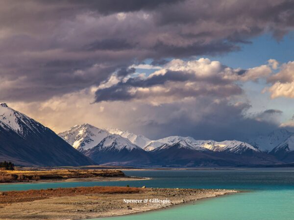 Snow-capped mountains with lake and cloudy sky