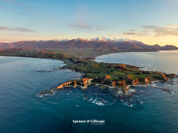 Aerial view of Kaikōura coastline and mountains at sunset.