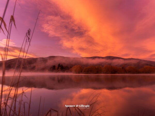 Serene lake at sunrise with misty hills