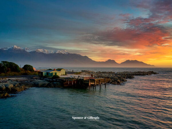 New Zealand coastal sunset, mountains in background.