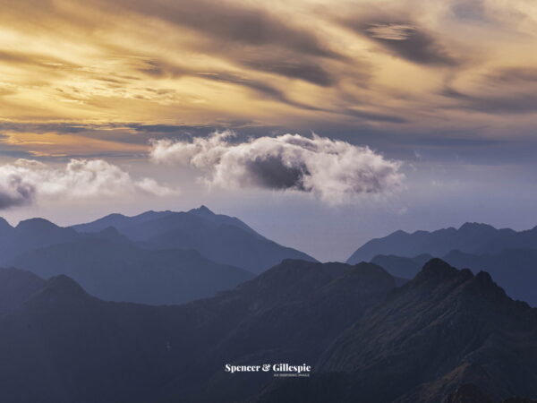 Mountain range at sunset with clouds.