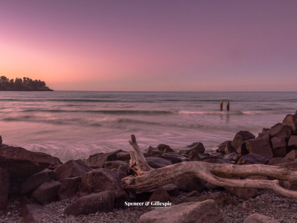 Rocky beach at sunset with driftwood