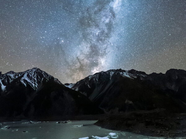 Starry sky above mountain and glacier lake.