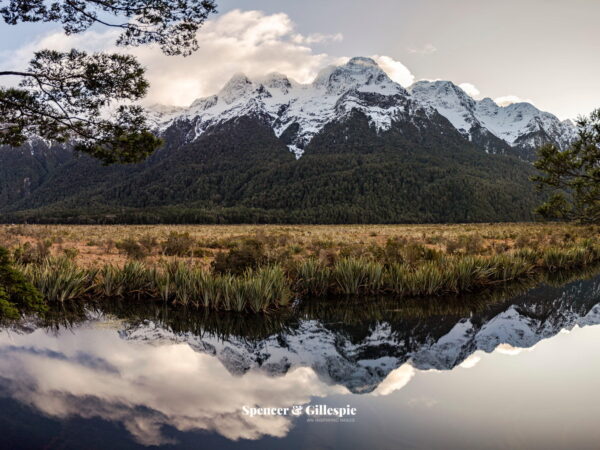 Snow-capped New Zealand mountains reflected in a lake.