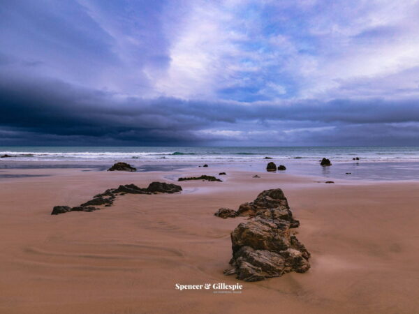 Rocks on a deserted beach, cloudy sky.