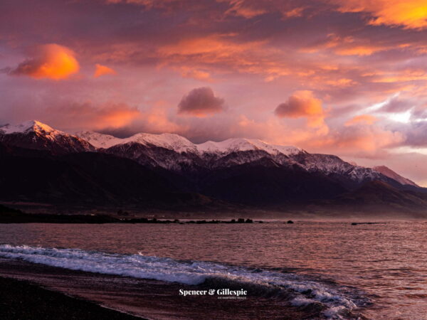 Sunset over Kaikoura mountains and ocean waves.