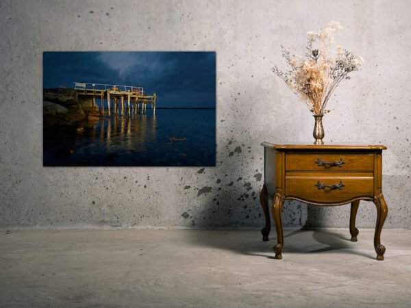 Wooden nightstand with vase and wall art.