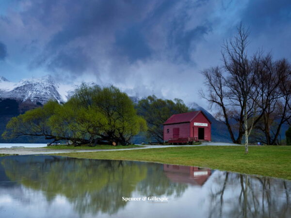 Glenorchy shed by tranquil lake with snowy mountains