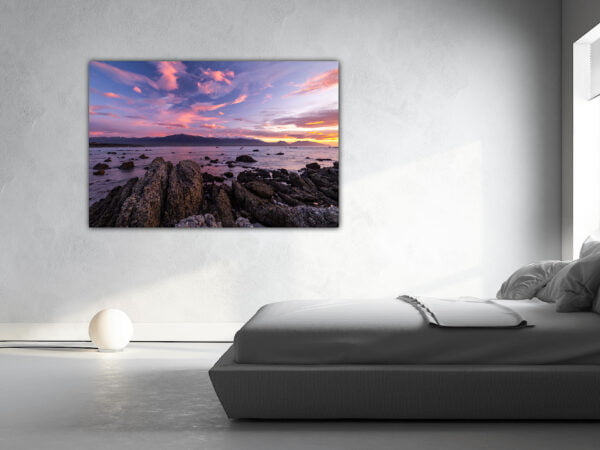 Bedroom with scenic ocean sunset painting.